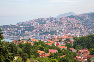 Fototapeta premium Elevated panoramic view of Zonguldak, a historic coal mining city on Turkey's Black Sea coast, featuring densely built hillside neighborhoods, lush greenery, and the coastal urban landscape.