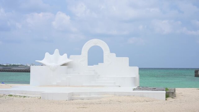 白い砂浜に建つギリシャ風のモニュメントとエメラルドグリーンの海