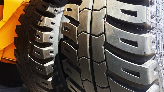 Close up of massive industrial tires on heavy duty construction vehicle, featuring rugged tread pattern, large size, powerful machinery for demanding terrain
