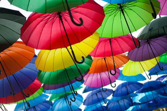Multicolored umbrellas create a dense decorative canopy against the sky, vibrant outdoor festival display, creative background.