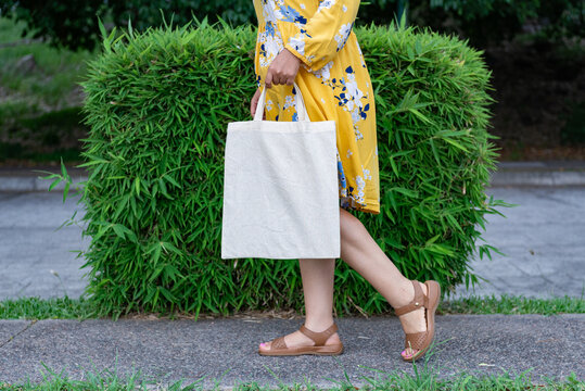 Woman in Yellow Floral Dress Carrying Blank Canvas Tote Bag Mockup Outdoors