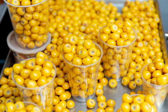 Fresh Yellow Jocote Fruits in Clear Plastic Cups at Traditional Street Market