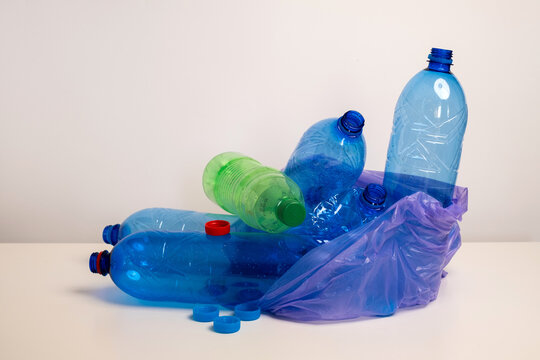 Empty blue plastic bottles and purple single use bag for recycling and environment protection concept