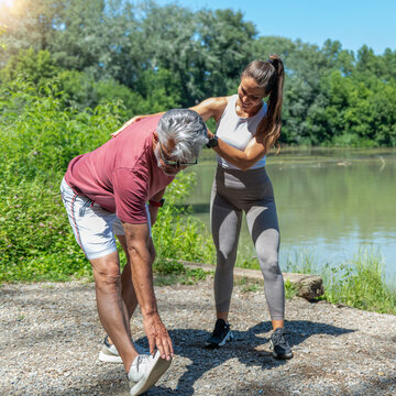 Flexibility training. Senior man performing a standing hamstring stretch while receiving guidance from a fitness coach to improve flexibility, posture, lower body mobility 