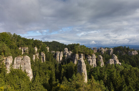 Panoramic view of sandstone rock towers rising above a dense green pine forest in Bohemian Paradise, Czech Republic