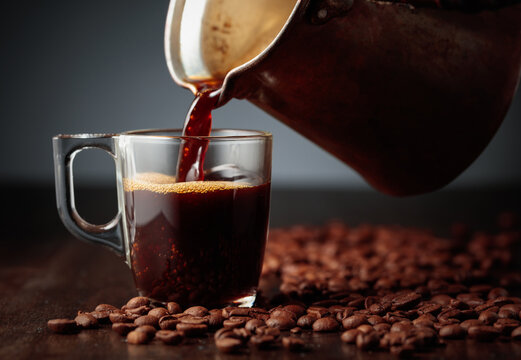 Black coffee is poured into a glass cup.