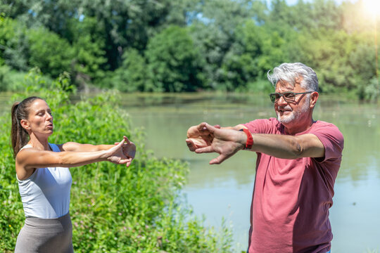 Senior participant practicing an upper body stretching exercise with instructor guidance to enhance shoulder mobility, posture, flexibility, muscle recovery, and overall physical wellness.