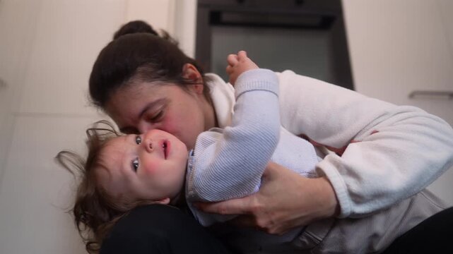 Mother embracing and kissing toddler, expressing unconditional love, emotional security and authentic family connection