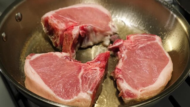 Cooking steaks in a metallic pan with a wooden spatula on a kitchen stove, viewed from a top-down angle, creating a neutral mood for a food preparation tutorial. The scene features red.