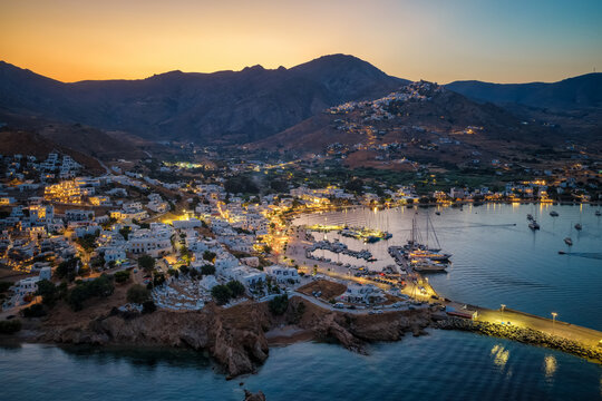 Aerial view of the illuminated town of Livadi, harbor and marina of Serifos island, during summer sunset time, Cyclades, Greece