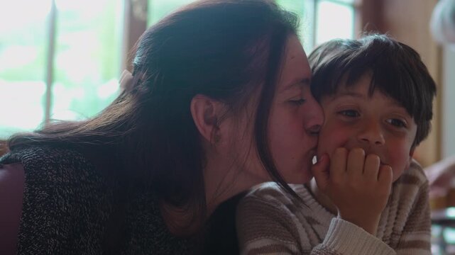 Close up mother kisses thoughtful son on the cheek at home, expressing unconditional love, emotional security, maternal care and secure family attachment