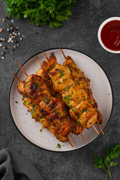 Juicy chicken skewers cooked in an air fryer and served on a plate with fresh herbs, cherry tomatoes and dipping sauce. Healthy food. Top view, copy space.