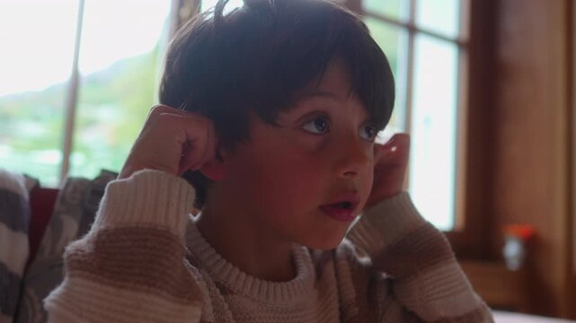 Thoughtful school age boy waits at restaurant table, expressing quiet patience, mild boredom, family dining and authentic everyday childhood