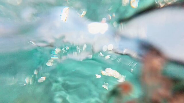 水中から見上げる透き通ったエメラルドグリーンの海と砂底の波模様