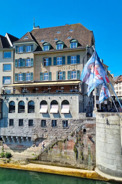 Basel, Switzerland, May 24, 2026: Historic Riverside Architecture with Flags in Zurich on a Sunny Day