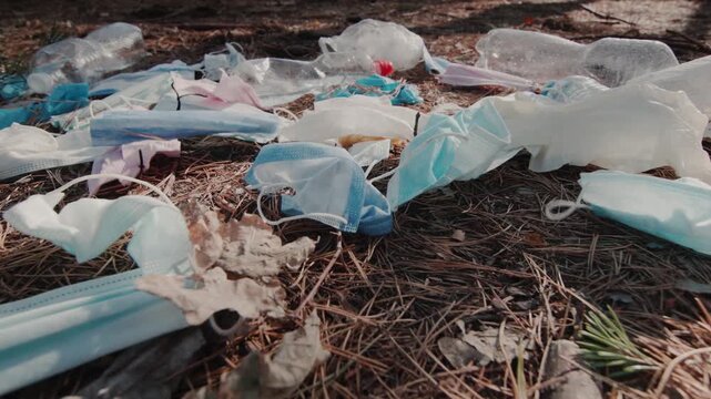 Disposed face masks and plastic waste littering natural environment, highlighting impact of pandemic on global pollution and urgent need for sustainable disposal solutions.