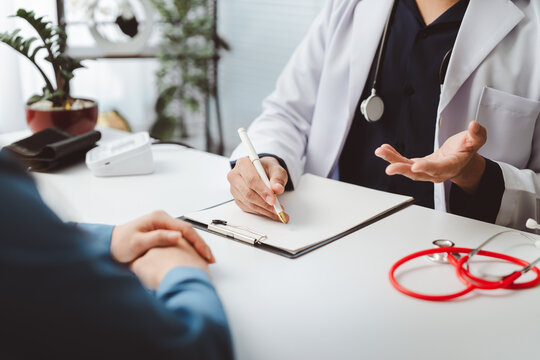 Doctor conducting a thorough medical consultation with patient, taking notes on clipboard while discussing symptoms, diagnosis and treatment plan for comprehensive care