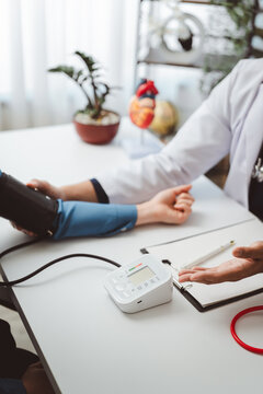 Doctor checking patient blood pressure, discussing heart health and risk factors, using a digital monitor for medical consultation and prevention of hypertension