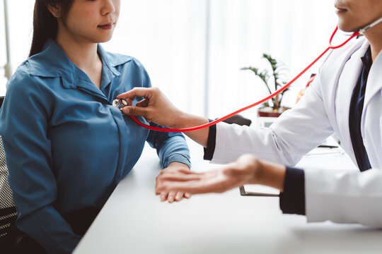 Doctor performing medical examination on patient using stethoscope, checking heart and lung sounds during health consultation for disease prevention and early diagnosis