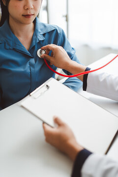 Doctor examining young patient, listening to her heart with a stethoscope during a routine medical check-up, emphasizing health prevention and professional consultation