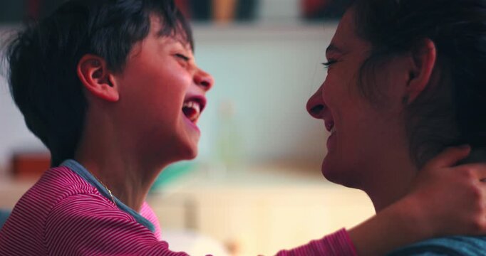 Mother and young son burst into laughter after touching foreheads, celebrating joyful connection, secure attachment and authentic family love