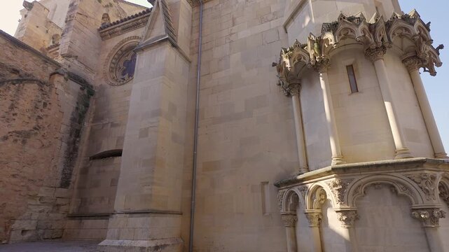 Side exterior view of Cuenca Cathedral with decorative apse and nearby plaza buildings in Spain