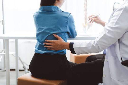 Woman experiencing lower back pain consulting doctor for medical advice and treatment, a healthcare professional examining and discussing spinal health issues with patient