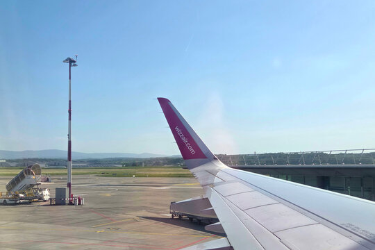 Basel, Switzerland, May 25, 2026: Aircraft Wing View with Clear Blue Sky at Modern Airport Terminal