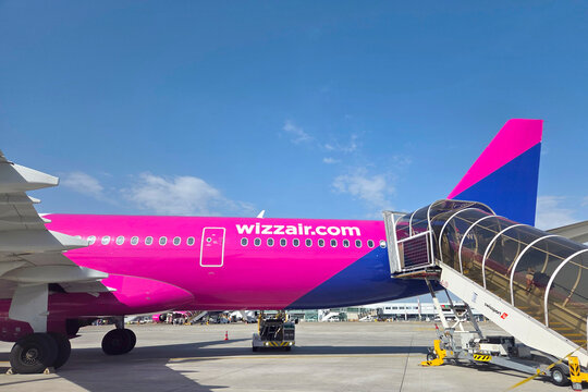 Basel, Switzerland, May 25, 2026: Colorful Wizz Air Plane at Airport with Boarding Ramp and Clear Blue Sky