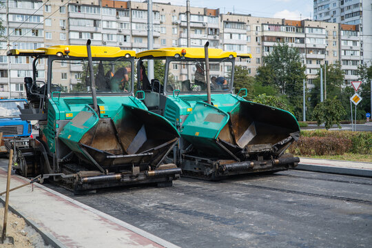 Two asphalt pavers machinery repairing city road in residential area