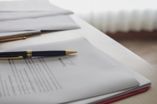 Luxury pen placed on signed business contract document on desk. Concept of approved deal, legal agreement, and completed transaction.