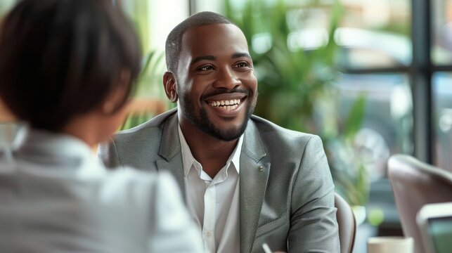 Businessman laughs during a friendly discussion with his partner in a bright and modern corporate workspace.