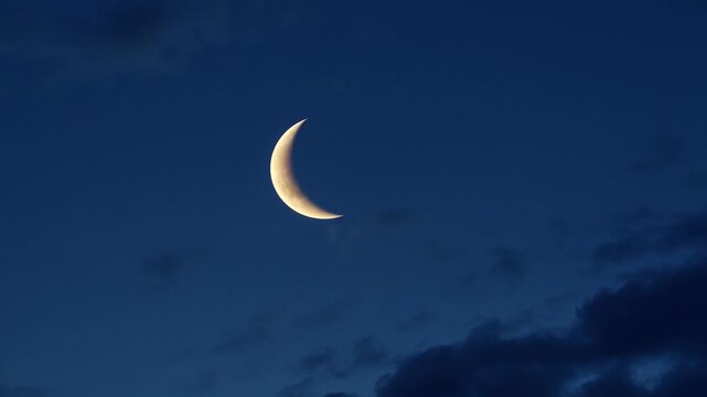 Crescent moon moving through dark night clouds, cinematic evening sky atmosphere