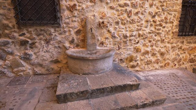 Medieval stone fountain against a rustic wall in the historic old town of Cuenca Spain