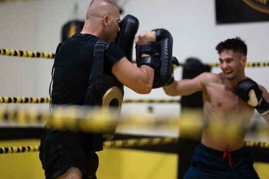 Boxer Training With Coach Holding Pads In Boxing Ring During Intense Sparring Session