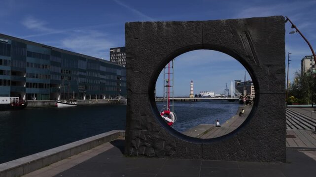 Waterfront view of stone sculpture and lighthouse in Malmo harbor, Sweden