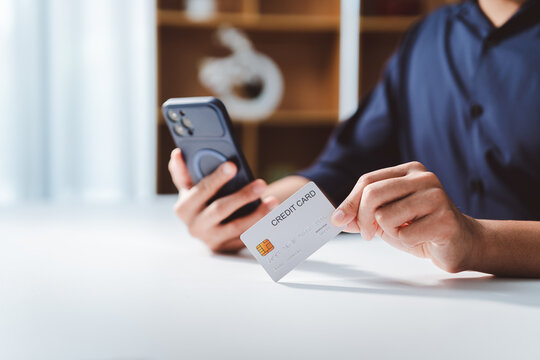 Person using a credit card to make an online payment via a smartphone, demonstrating convenient and secure financial transactions and digital shopping at home