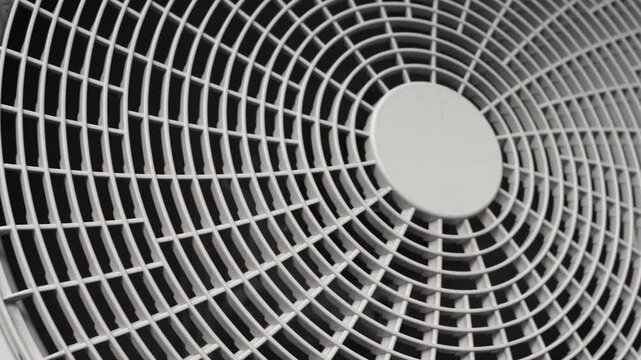 Panning across the plastic grill of an outdoor air conditioner unit. Concept of HVAC systems, cooling technology, and home ventilation.