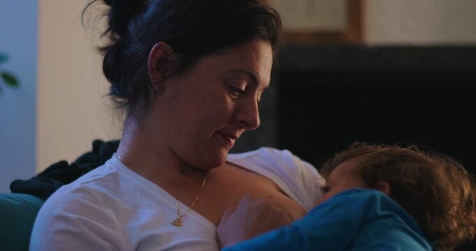 Mother breastfeeding baby while smiling at home, nurturing secure attachment, maternal warmth and emotional connection during a peaceful everyday family bonding moment