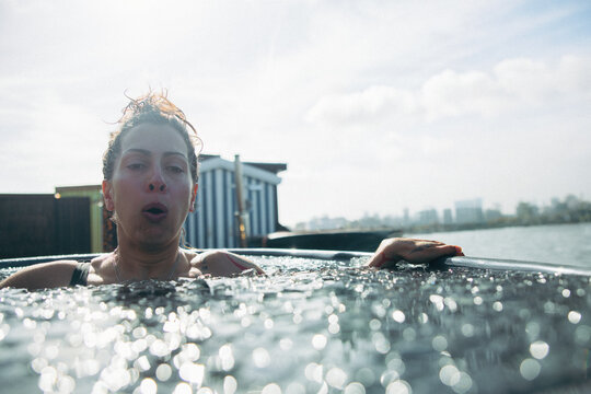 Woman in cold water ice bath for recovery, wellness, therapy, and outdoor health routine.