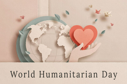 Minimalist flat lay paper cut style for world humanitarian day showing human hand holding red heart shapes next to pastel green earth globe and flying origami paper cranes on beige backdrop.