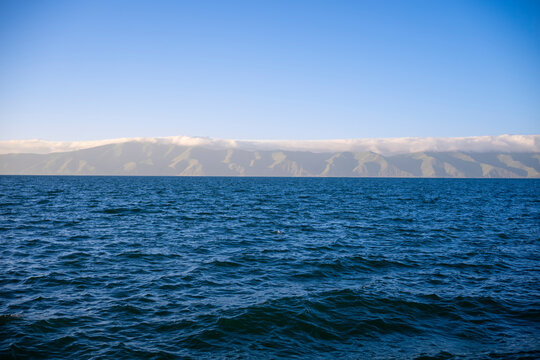 Deep Blue Wavy Water Surface looking towards Distant Foggy Mountain Range