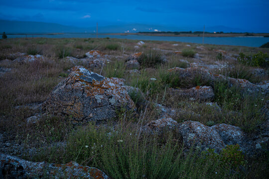 Mossy Boulders and Rocky Field at Dusk overlooking Lake in Twilight