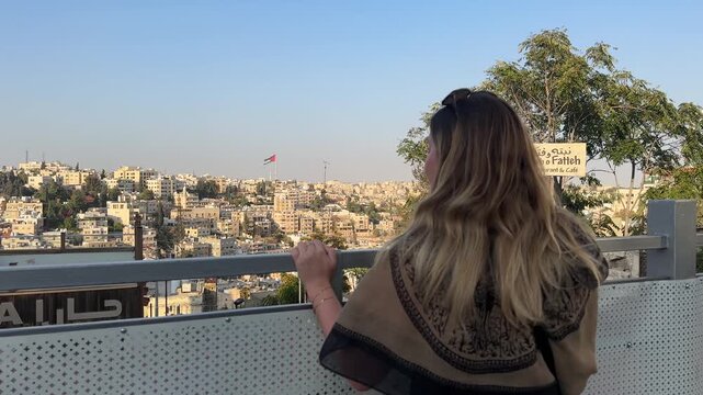 Captivating footage of a woman gazing out over the sweeping urban panorama of Amman City, soaking up the vibrant atmosphere of one of the Middle East's most historic and captivating capitals, Jordan.