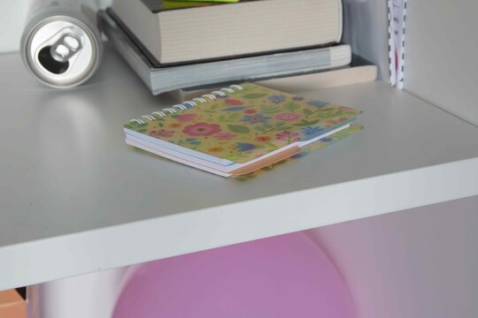 Notebook and books on shelf with a soda can at home, showing daily study setup in the afternoon