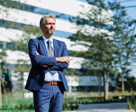 Portrait of a happy smart inteligent senior businessman smiling standing in the front of the office building
