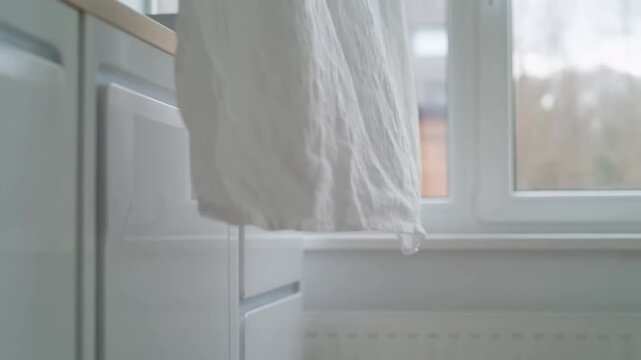 Soft White Linen Fabric Hanging Indoors Near Kitchen Cabinets and Window for Home Interior Concept