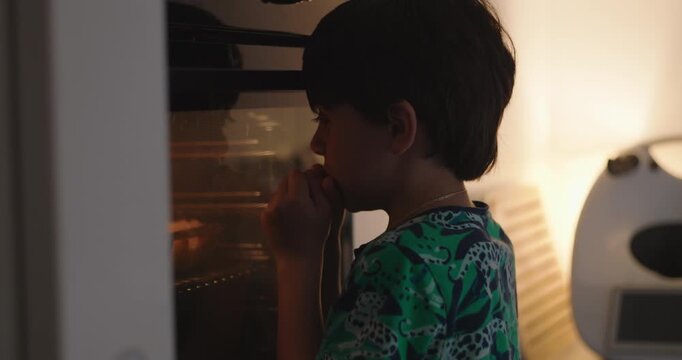 Young boy watching food bake in oven at home, waiting with excitement and curiosity while anticipating a homemade meal during everyday family life