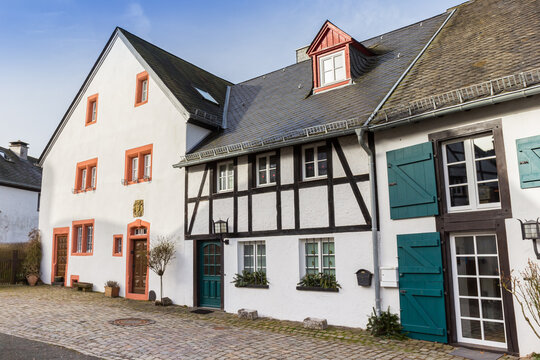 Half timbered houses line a historic cobblestone street in Kronenburg, Germany