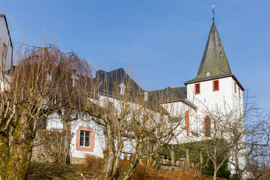 Historic white church on a hillside slope in Kronenburg, Germany